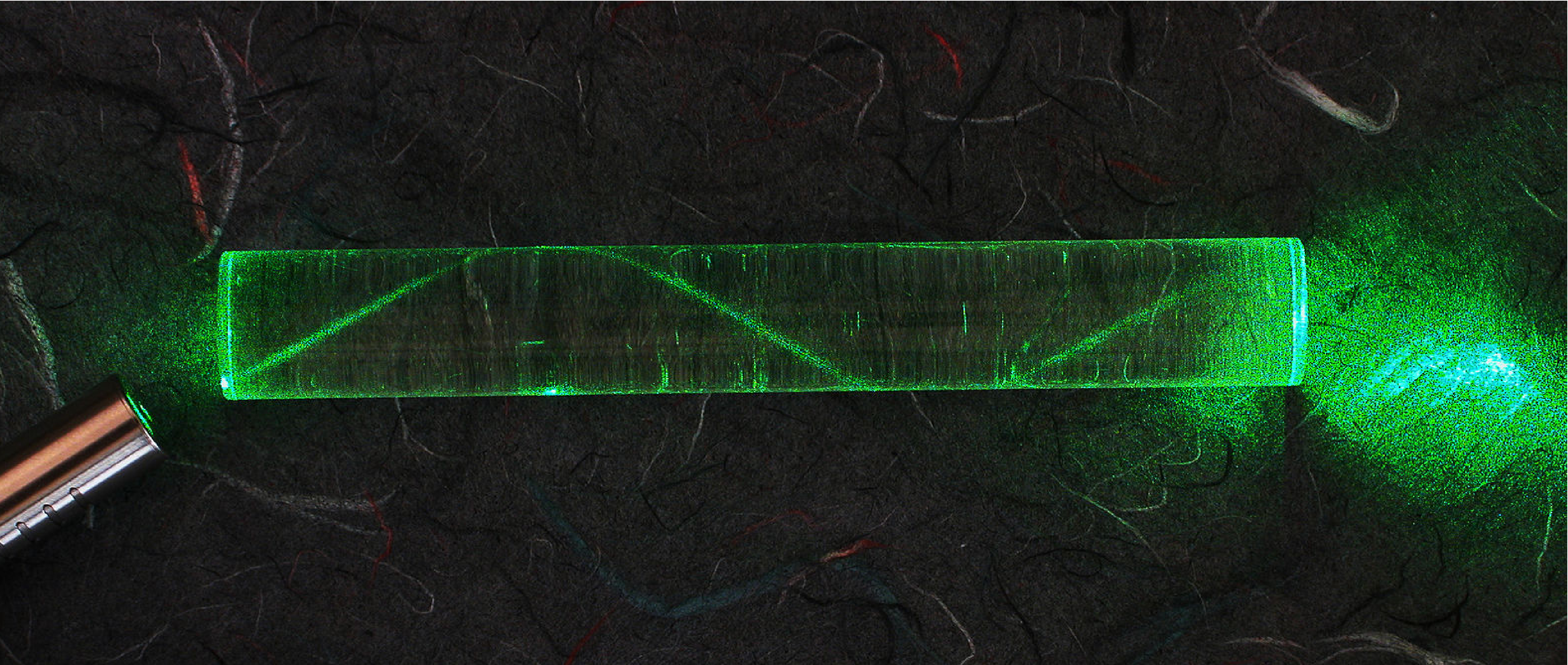 Laser light travels through a rod at the bottom left and reflects off the internal surfaces of the rod creating a zigzag shape. Points of reflection appear to be displaced from points of incidence.