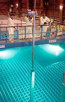 A spent fuel rod being lowered into a storage grid in a pool of water at a nuclear power plant. Source: U.S. DoE.
