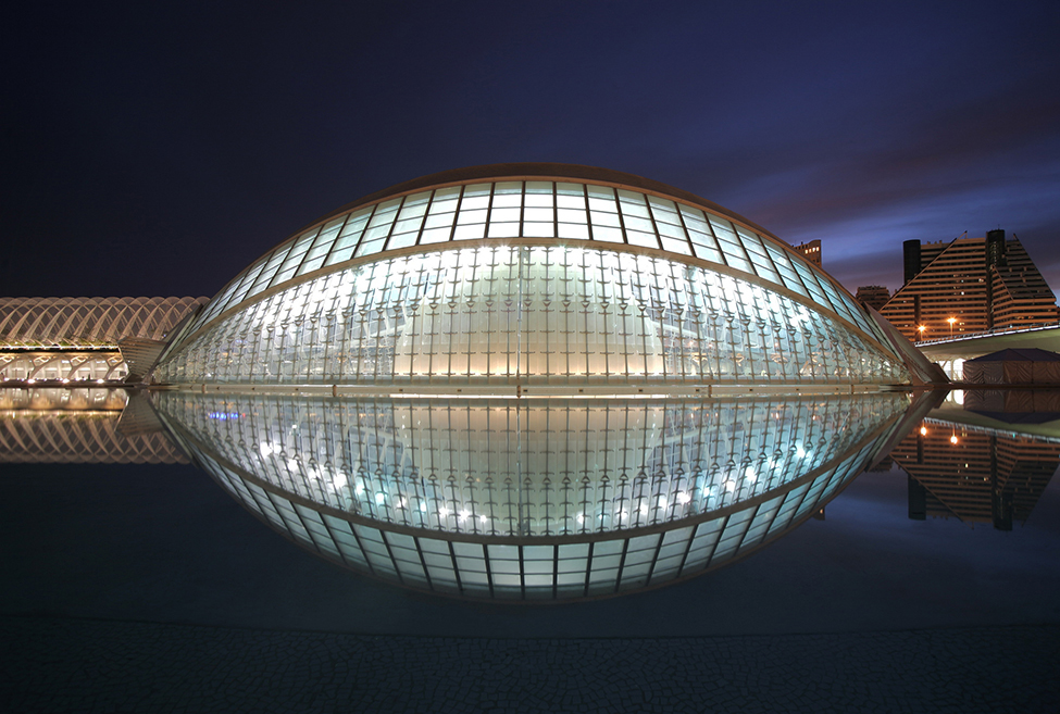 A photo of a glass ovoid dome reflecting in the water to make something like a football shape.