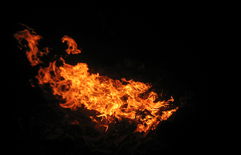 Vibrant orange and yellow flames dance against the dark night, creating a mesmerizing and intense glow.